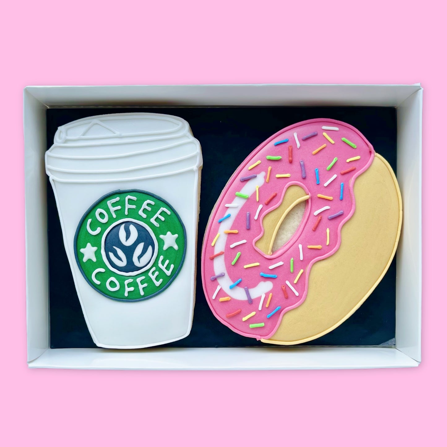 hand iced white coffee cup and pink donut with rainbow sprinkles biscuits in a open white gift box by Katie's Biscuit shop