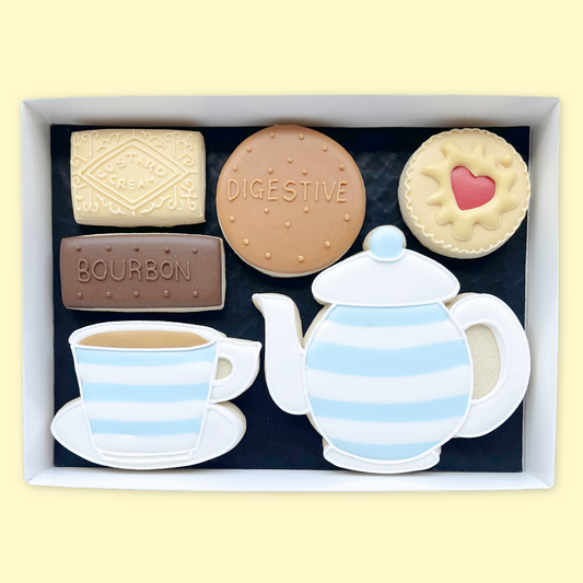 Hand iced tea pot and cup with custard cream, bourbon, digestive and jammy dodger in an open white gift box by Katie's biscuit shop