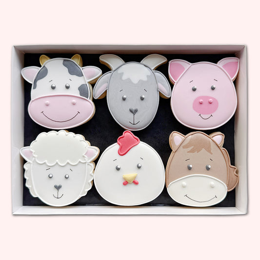 Six hand-iced animal-face biscuits in a white gift box, featuring a cow, goat, pig, sheep, chicken and horse.