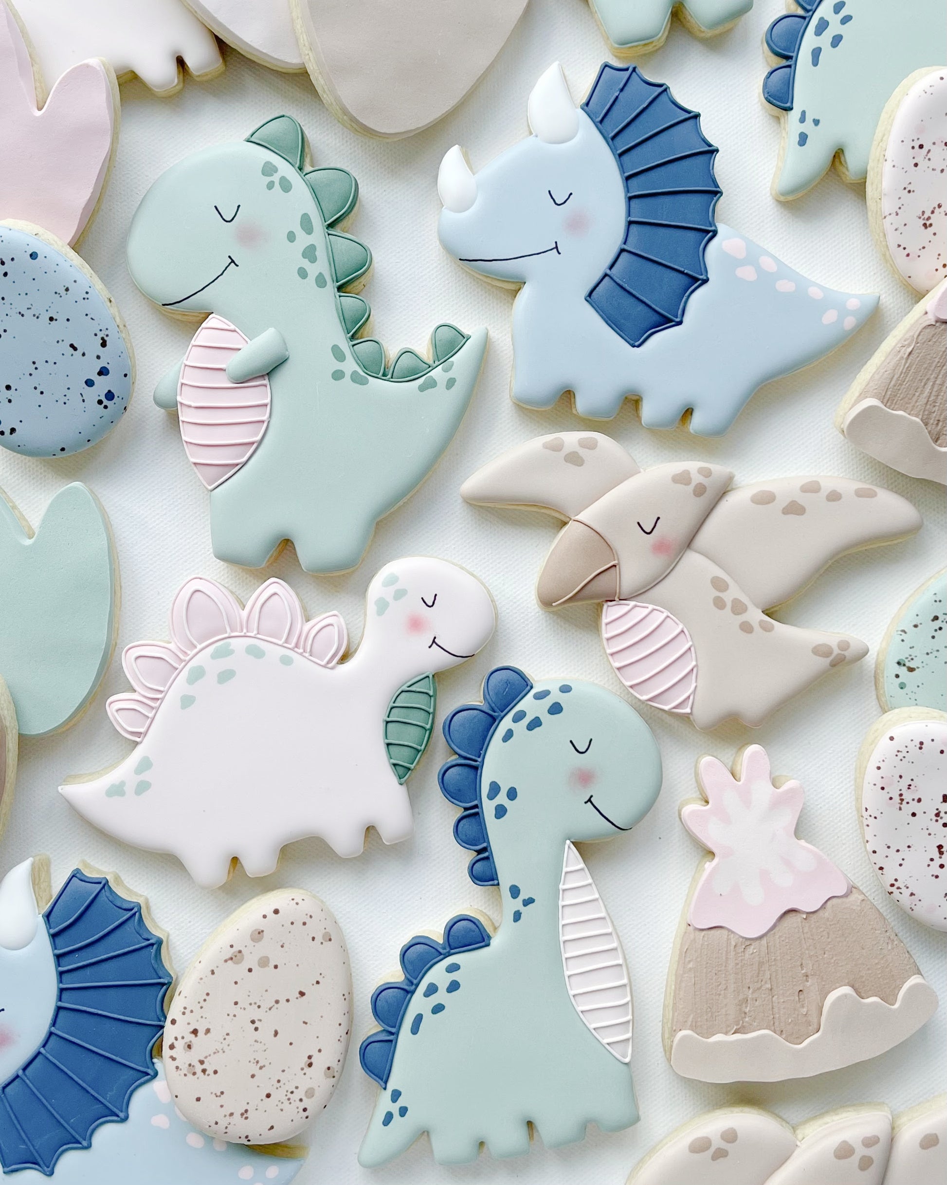 Dinosaur decorated cookies in muted pastels of greens and blues and pinks 