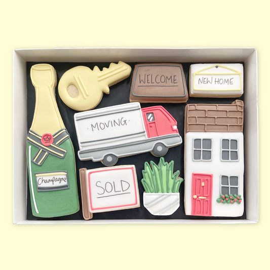 Gift box of new home iced biscuits featuring a house, key, moving van, champagne bottle, plant and signs reading ‘Welcome’, ‘New Home’ and ‘Sold
