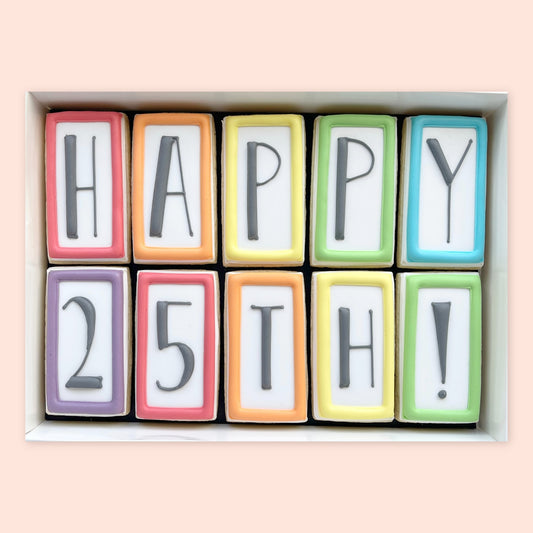 Ten rectangular iced biscuits with colourful borders and grey lettering spelling ‘HAPPY 25TH!’, arranged in a white gift box.