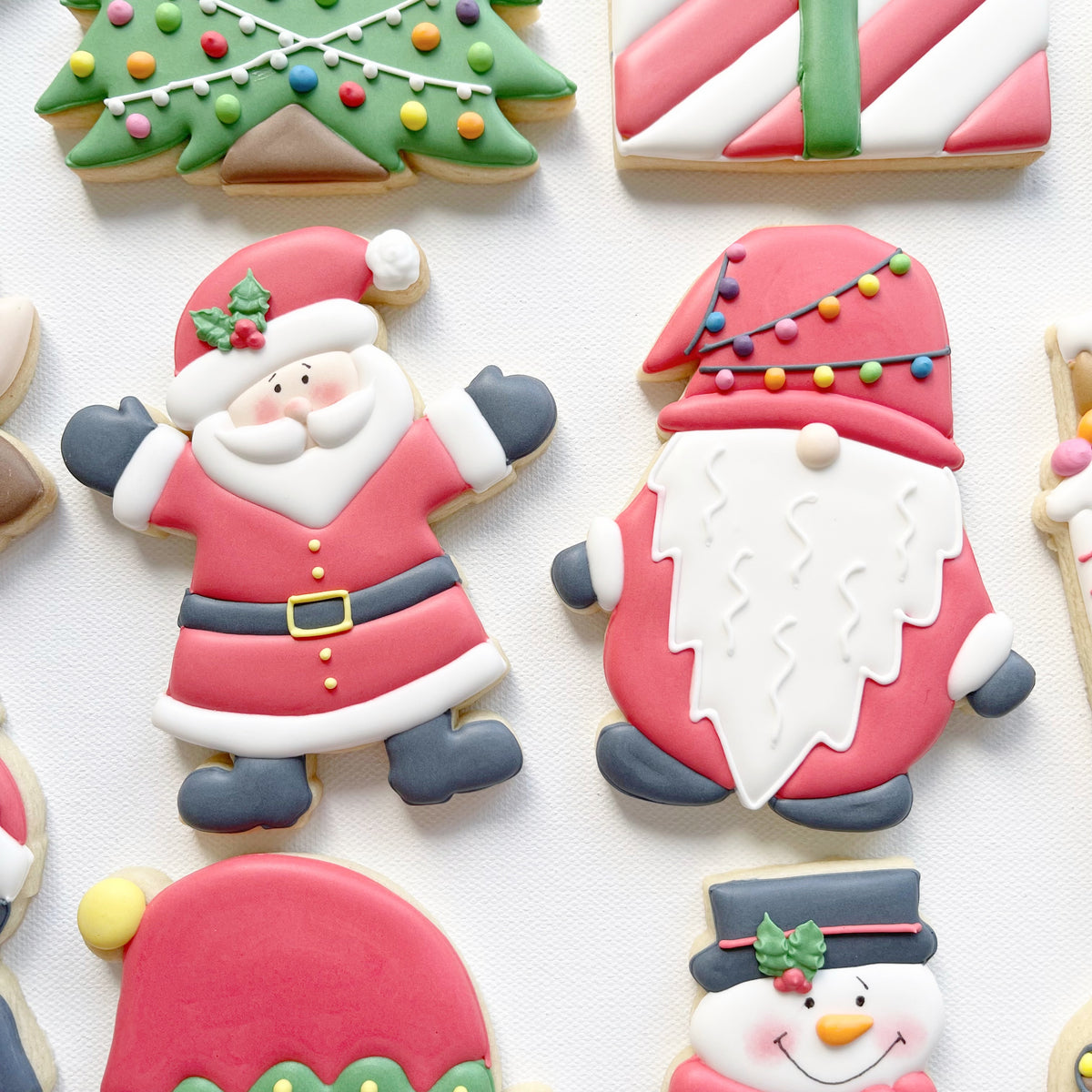 Santa and Christmas Gonk Biscuits
Hand-iced Santa biscuit with raised arms beside a red Christmas gonk biscuit with a long white beard and colourful lights on its hat.