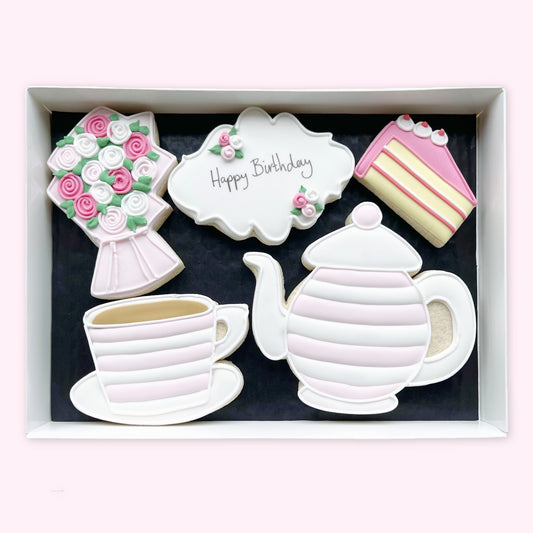 Hand-iced biscuits in a white gift box, featuring a pink-striped teapot and teacup, flower bouquet, cake slice and ‘Happy Birthday’ plaque
