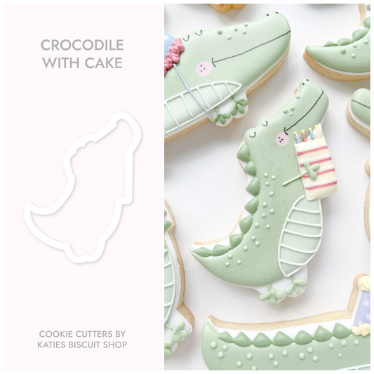 3D printed cookie cutter by katies biscuit shop in the shape of a crocodile holding a cake 