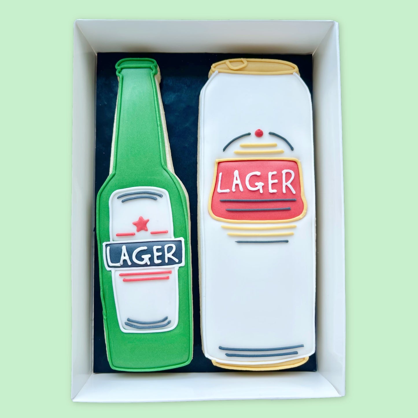 hand iced green bottle of lager and white can of lager biscuits in a open white gift box by Katie's Biscuit shop