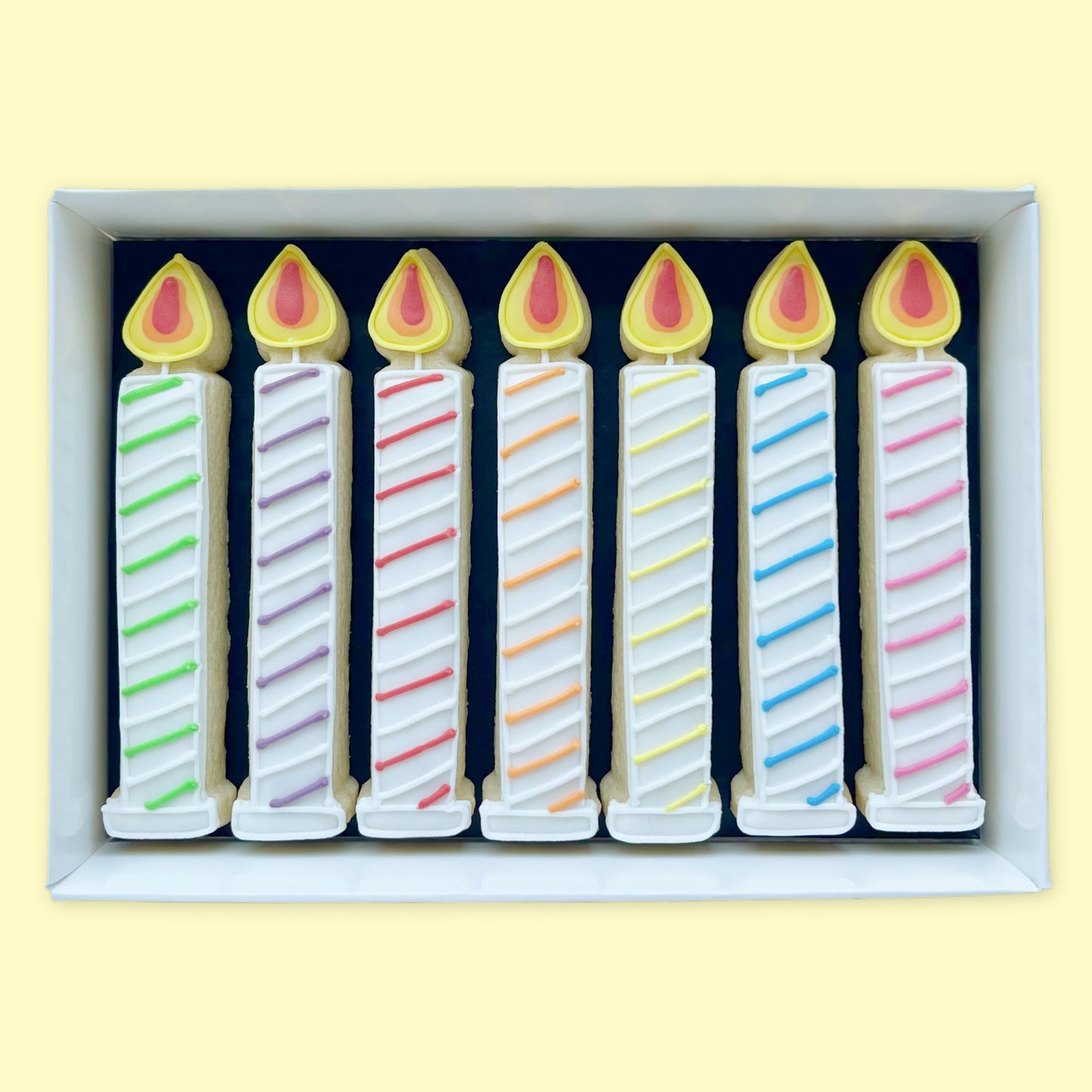 Hand iced birthday candles biscuits in rainbow shades in an open white gift box by Katie's biscuit shop