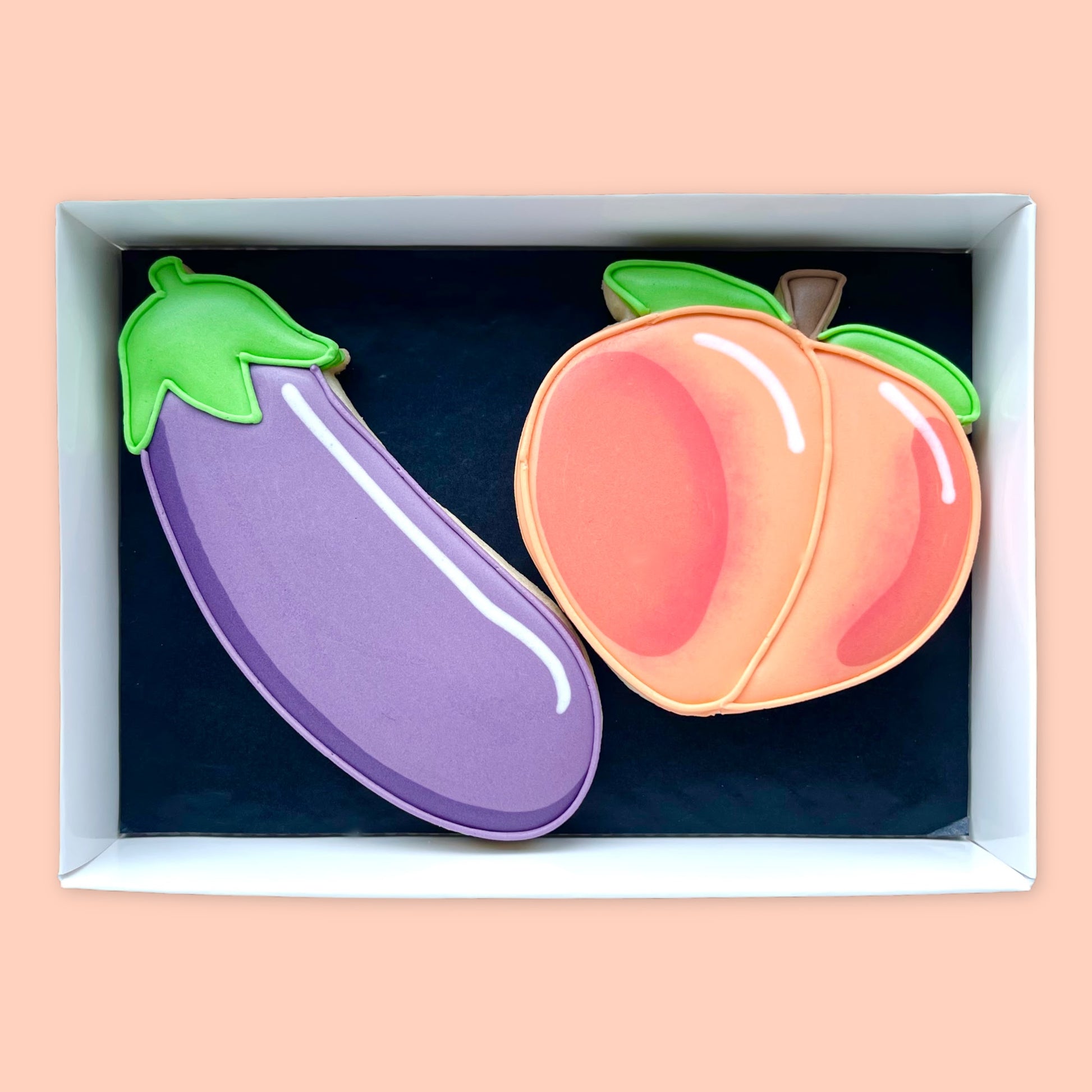 Hand iced peach and aubergine emoji biscuits in a open white gift box by Katie's biacuit shop