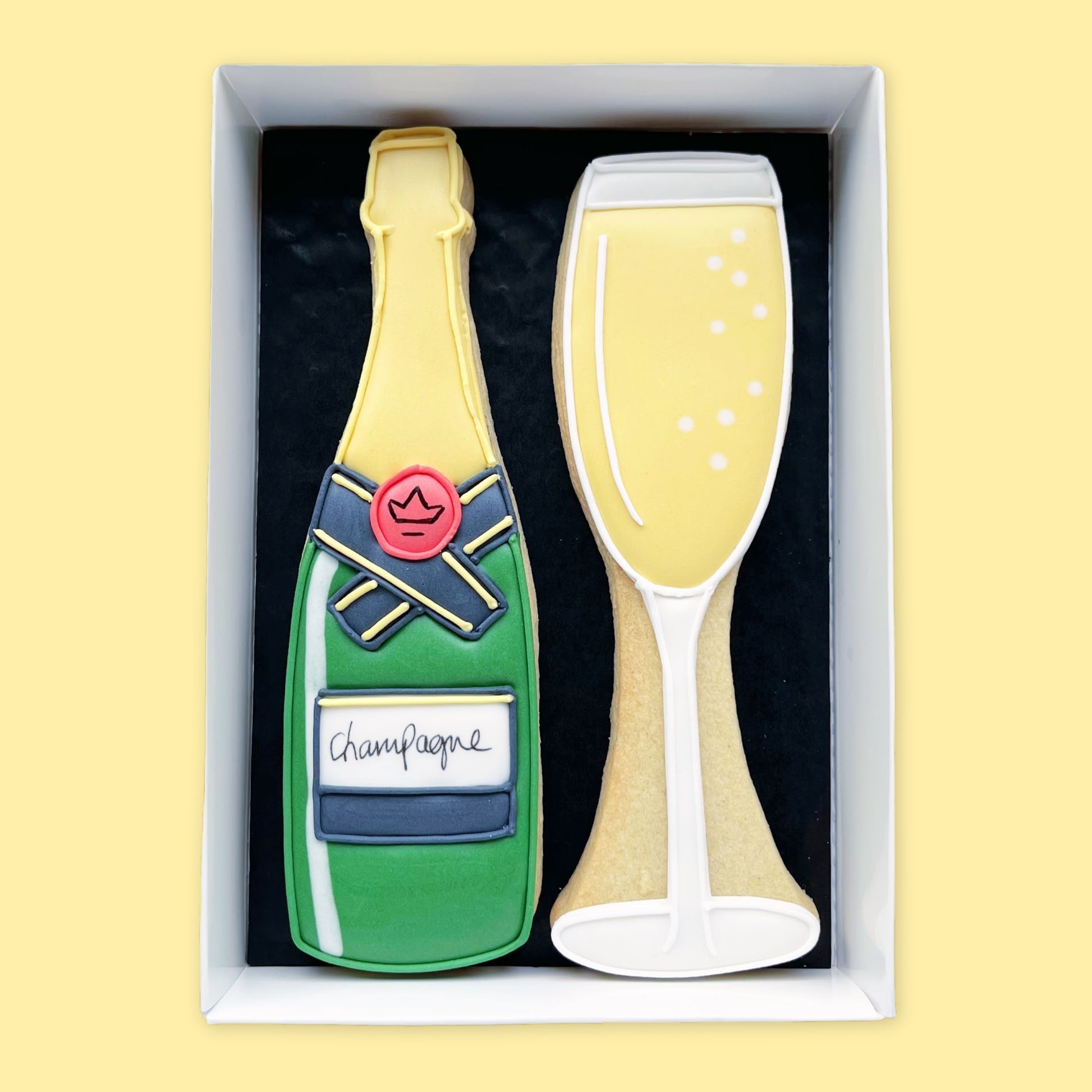 hand iced bottle of champagne and glass with bubbles biscuits in an open white gift box by katie's biscuit shop