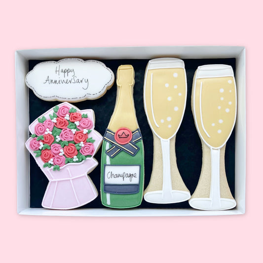 Hand-iced anniversary biscuits in a white gift box, featuring a champagne bottle, two glasses, flowers and a Happy Anniversary plaque