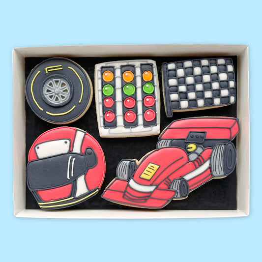 Gift box of racing-themed iced biscuits shaped as a red race car, racing helmet, wheel, chequered flag and starting lights.
