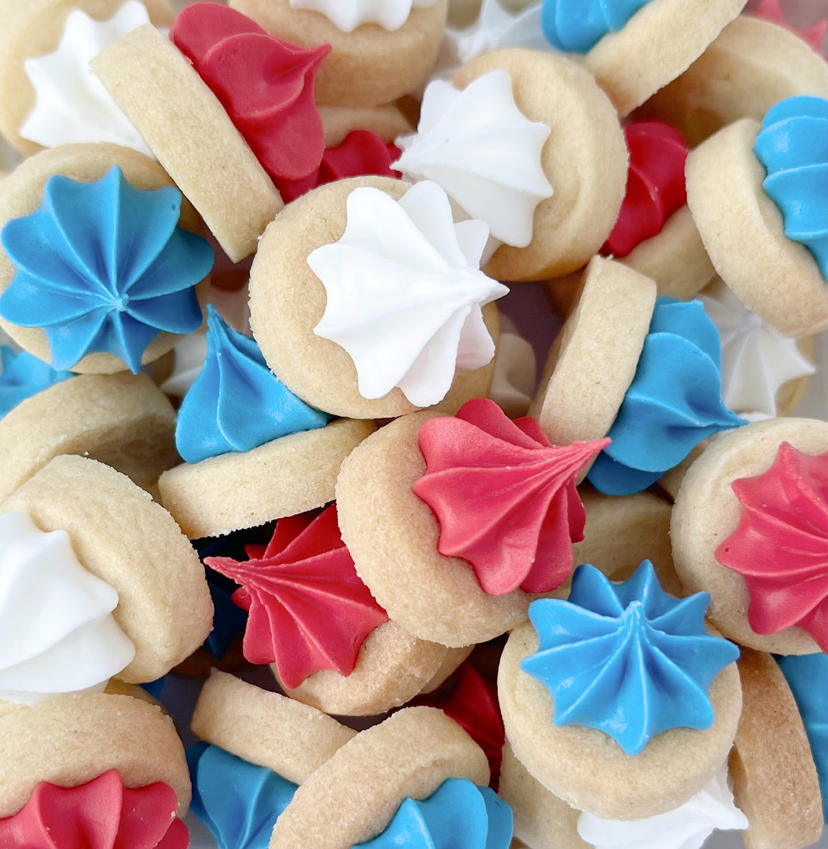 Close-up of mini round biscuit gems topped with piped red, white and blue icing.